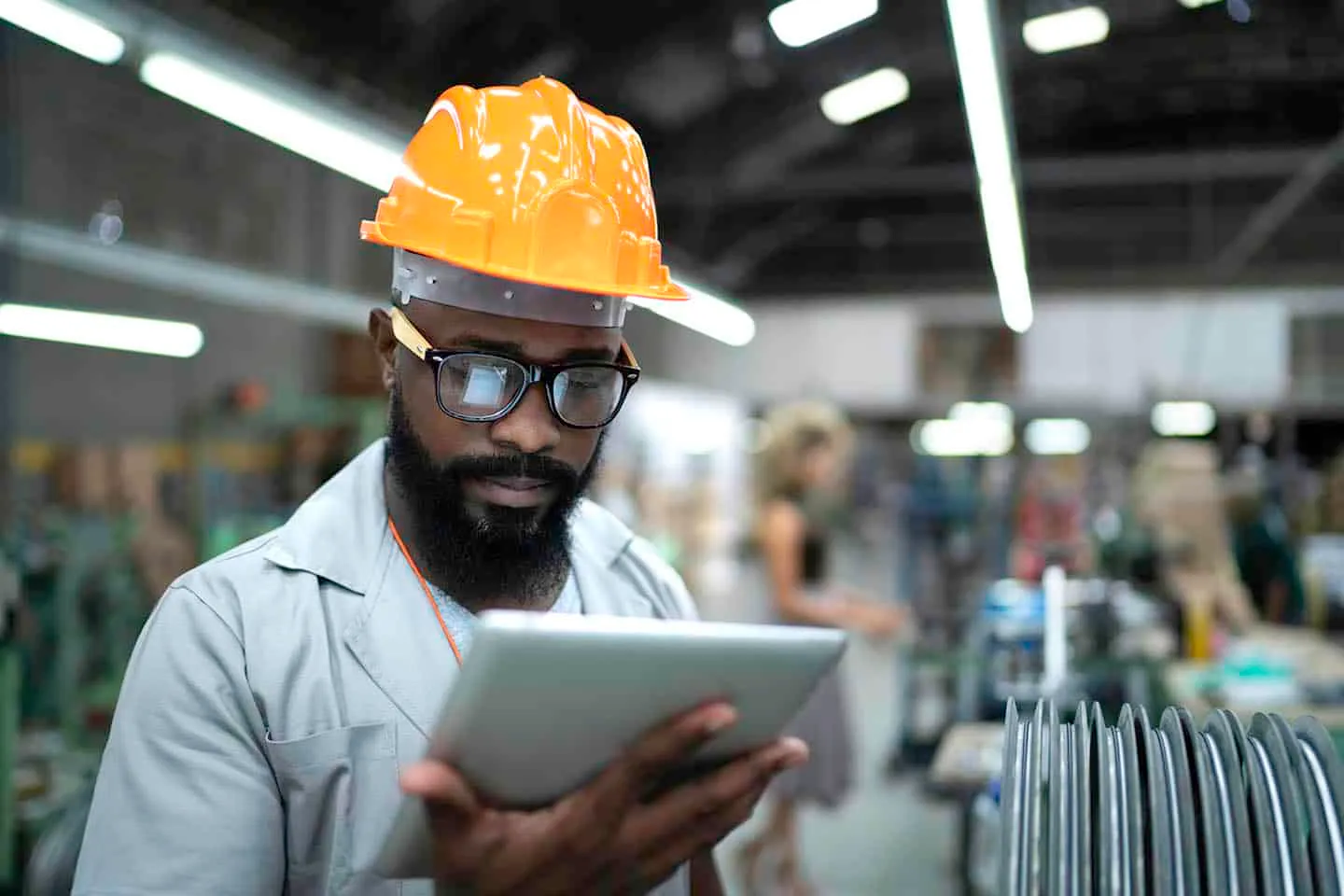 Factory worker in a hard hat reading instructions on a tablet